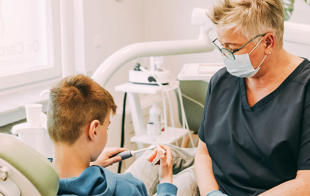 Eine Mitarbeiterin zeigt einem jungen Patienten ein Instrument in der Zahnarztpraxis Dr. Carolin Röder in Dinslaken